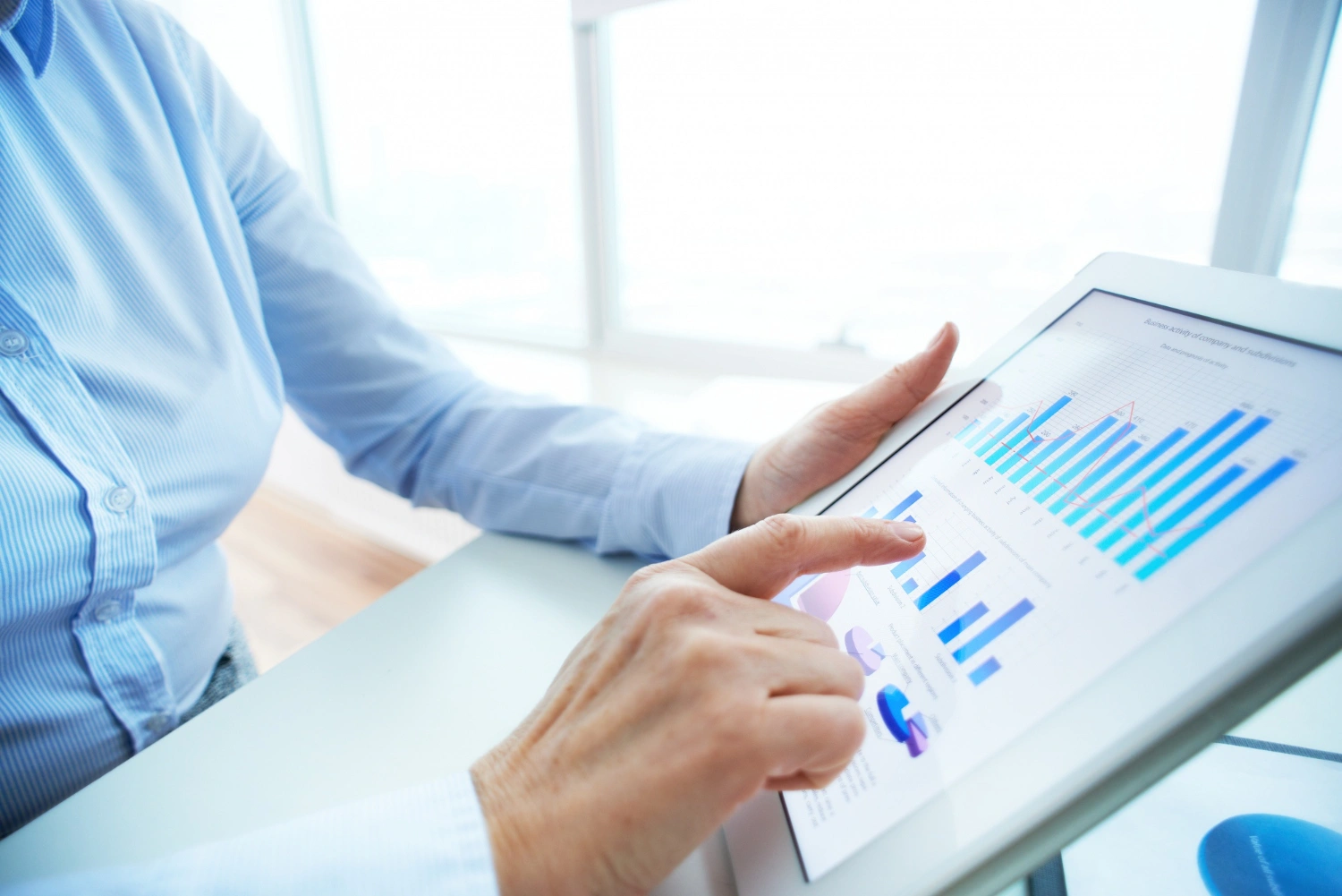 Person using a tablet to analyze graphs and charts with financial data.